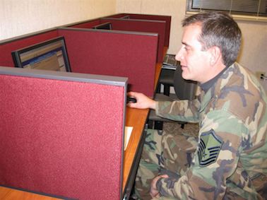 Militaire tenant une souris d'ordinateur et assis face à un écran